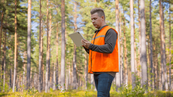 Inspector wearing an orange safety vest, submitting a form via tablet