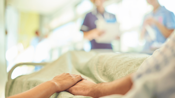 Hospital patient holding hands with a loved one