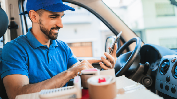 Driver smiling as he uses a tablet to manage his daily stops